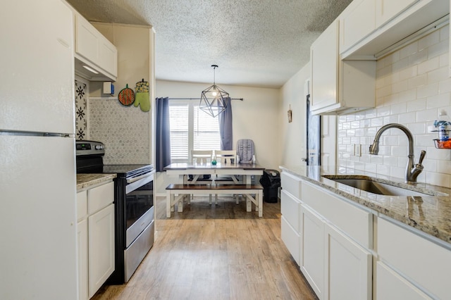 kitchen with tasteful backsplash, white cabinetry, sink, white fridge, and electric range