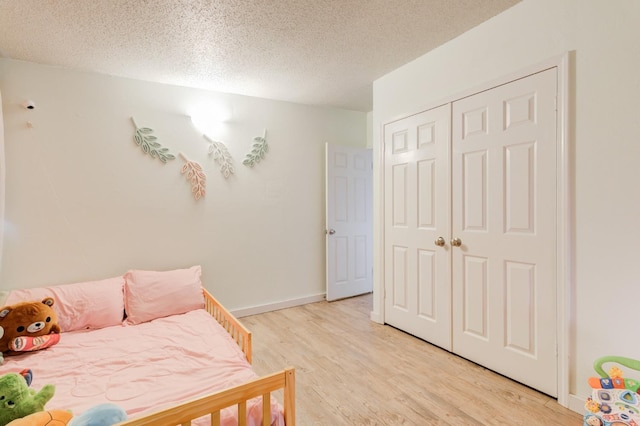 bedroom with a textured ceiling, light wood-type flooring, and a closet