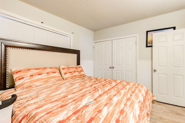 bedroom featuring light hardwood / wood-style floors, a closet, and a textured ceiling