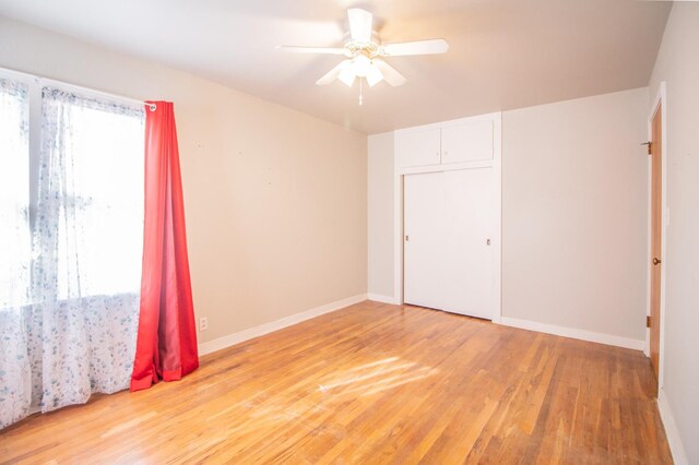 unfurnished bedroom with multiple windows, hardwood / wood-style flooring, a closet, and ceiling fan