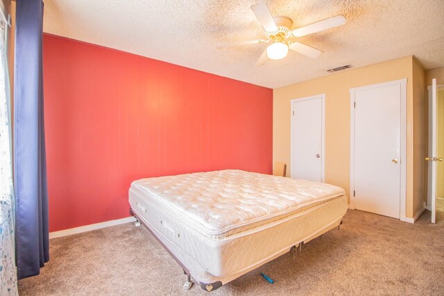 carpeted bedroom with ceiling fan and a textured ceiling