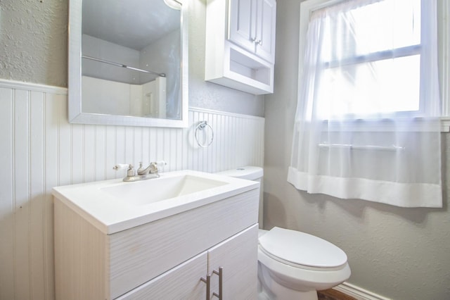 bathroom with walk in shower, vanity, and toilet