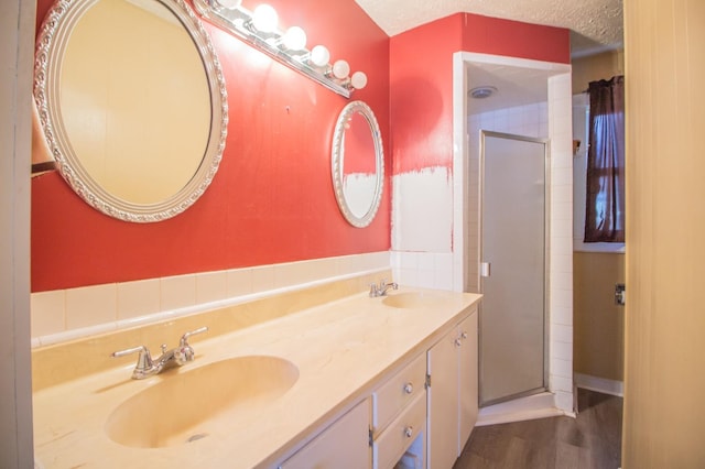 bathroom featuring walk in shower, vanity, hardwood / wood-style floors, and a textured ceiling