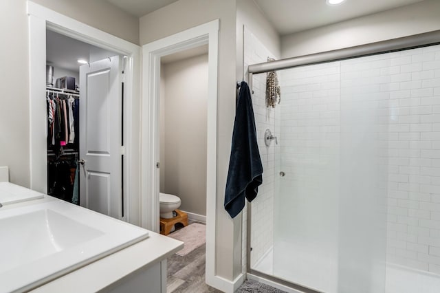 bathroom featuring wood-type flooring, toilet, vanity, and walk in shower