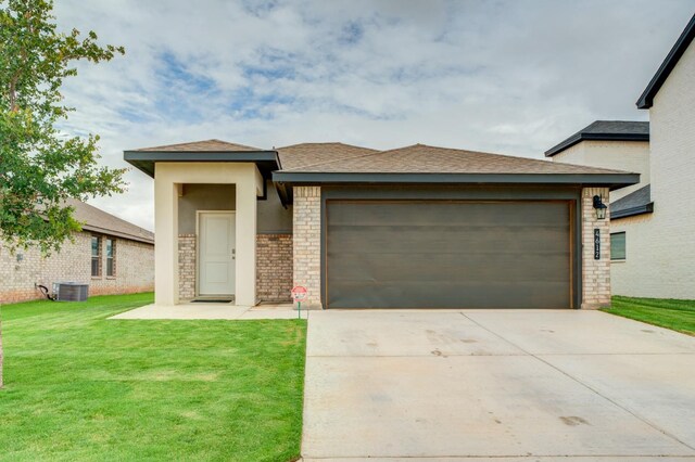 prairie-style house with a garage, cooling unit, and a front lawn