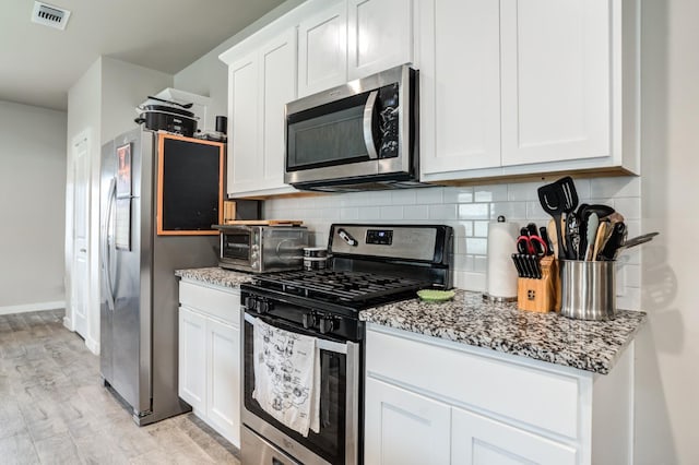 kitchen with white cabinets, decorative backsplash, light hardwood / wood-style floors, stainless steel appliances, and light stone countertops