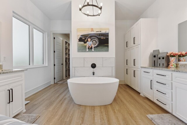 bathroom featuring wood-type flooring, a tub, vanity, and a chandelier