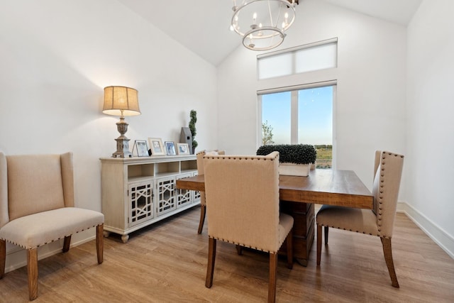 dining room with lofted ceiling, light wood-type flooring, and a notable chandelier