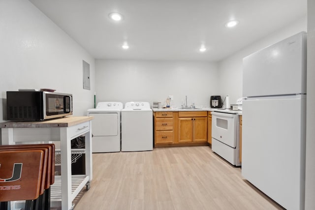 kitchen featuring sink, white appliances, electric panel, washer and dryer, and light wood-type flooring