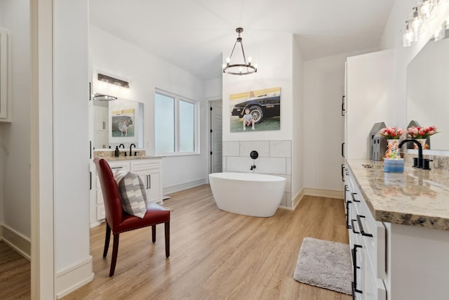 bathroom featuring an inviting chandelier, vanity, a bathing tub, and wood-type flooring