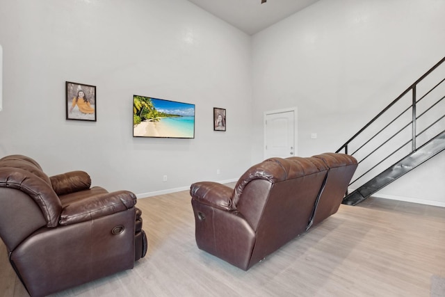 living room with light hardwood / wood-style floors and a high ceiling