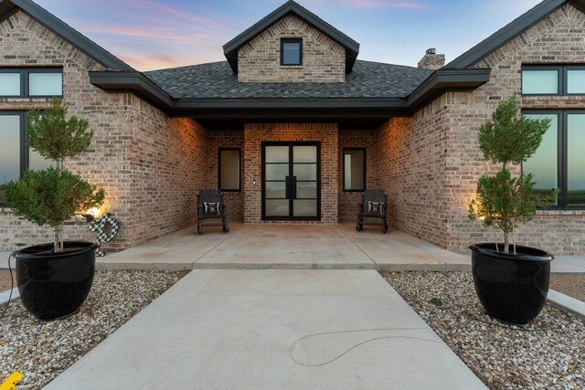 exterior entry at dusk featuring a patio