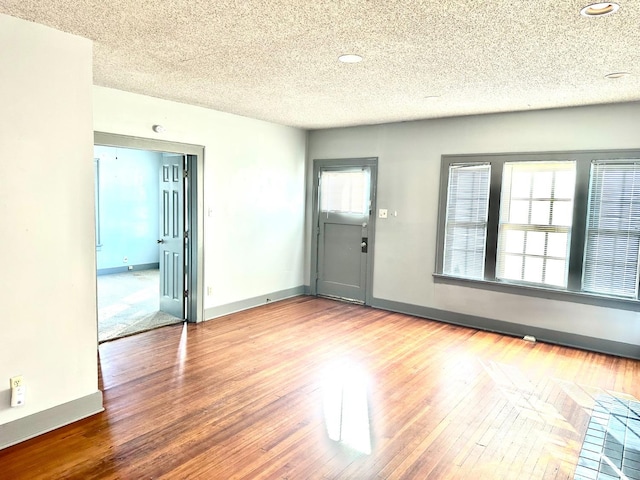 empty room with hardwood / wood-style flooring and a textured ceiling