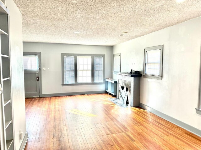 unfurnished living room with light hardwood / wood-style floors and a textured ceiling