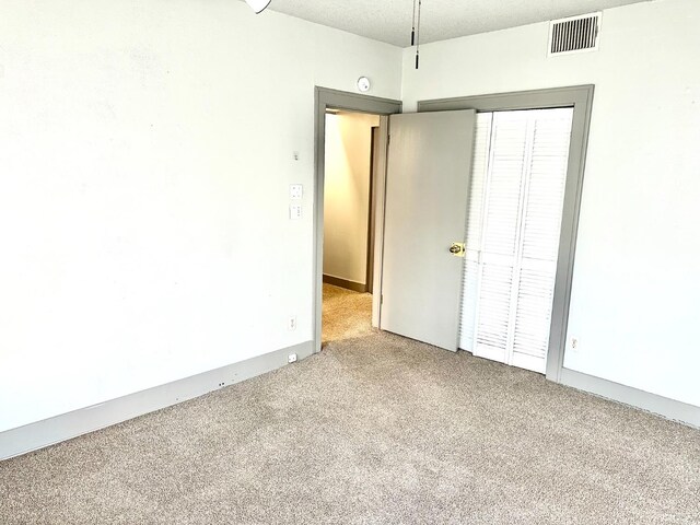 carpeted empty room with a textured ceiling