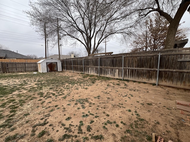 view of yard with an outbuilding, a storage unit, and a fenced backyard