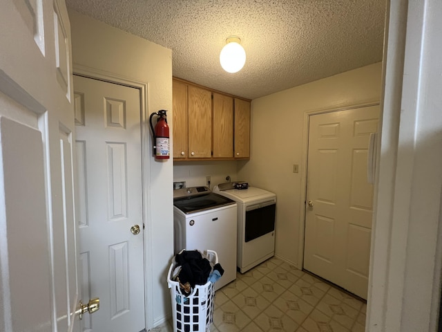 clothes washing area with cabinet space, a textured ceiling, and separate washer and dryer