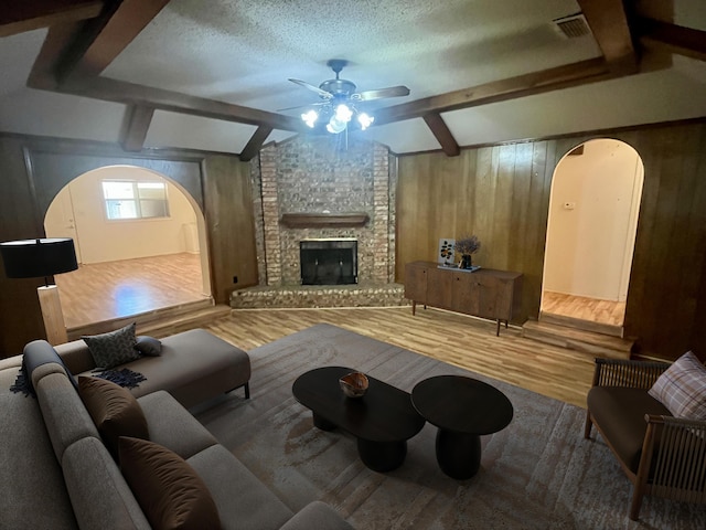 5013 57th St, Lubbock, TX 79414 - living area featuring arched walkways, a ceiling fan, wood finished floors, wooden walls, and a fireplace