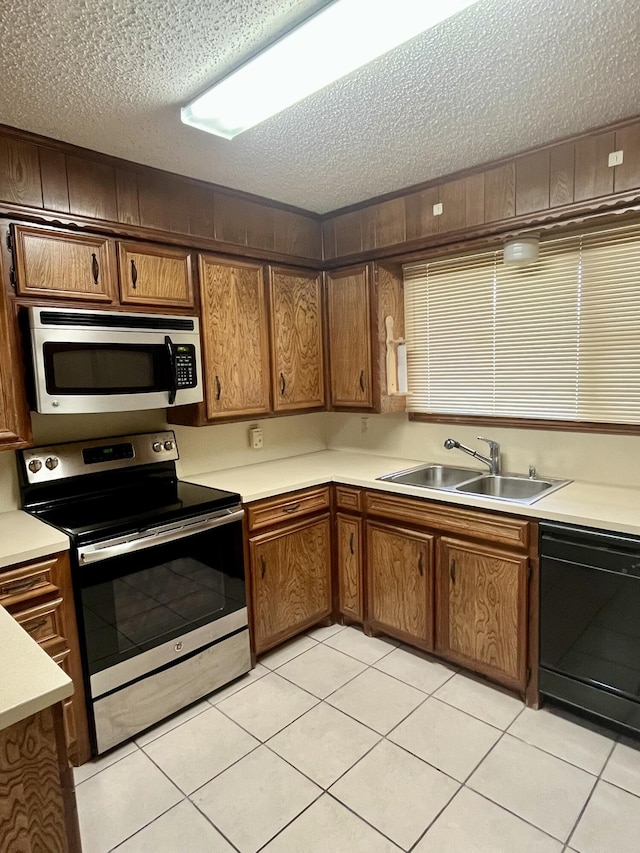 5013 57th St, Lubbock, TX 79414 - kitchen featuring appliances with stainless steel finishes, a textured ceiling, brown cabinets, light countertops, and light tile patterned floors
