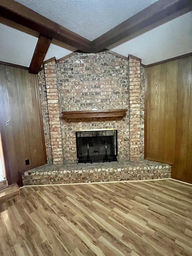 5013 57th St, Lubbock, TX 79414 - unfurnished living room with wood finished floors, wood walls, a textured ceiling, and a fireplace