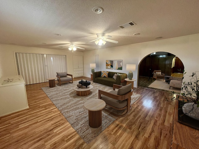 5013 57th St, Lubbock, TX 79414 - living room featuring arched walkways, wood finished floors, a textured ceiling, and ceiling fan
