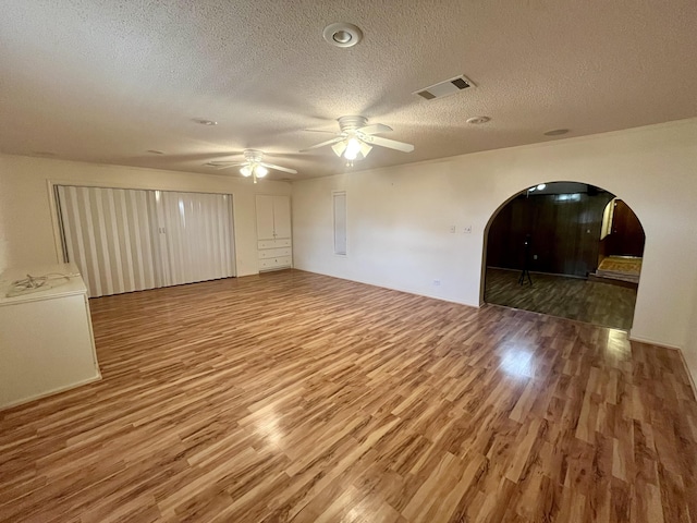 5013 57th St, Lubbock, TX 79414 - unfurnished room featuring arched walkways, wood finished floors, a textured ceiling, and ceiling fan