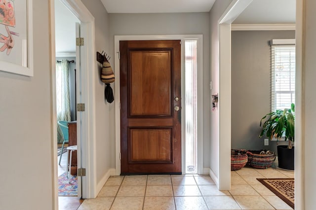 foyer entrance featuring crown molding and light tile patterned flooring