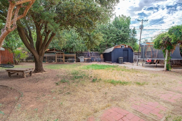 view of yard with a trampoline, a patio, and a storage unit