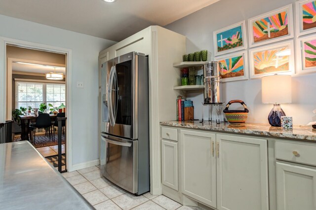 kitchen with stainless steel refrigerator with ice dispenser, light stone countertops, and light tile patterned floors