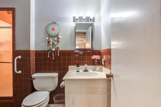 bathroom featuring vanity, tile walls, and toilet