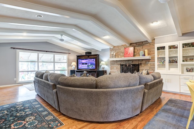 living room featuring lofted ceiling with beams, hardwood / wood-style flooring, and a fireplace