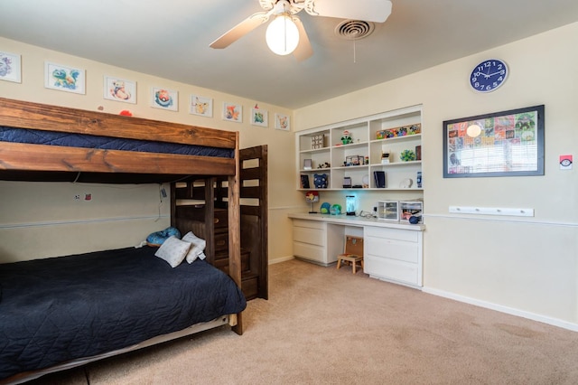 carpeted bedroom featuring built in desk and ceiling fan