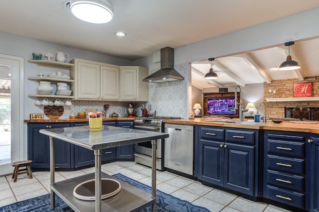 kitchen with blue cabinets, stainless steel appliances, and wall chimney range hood