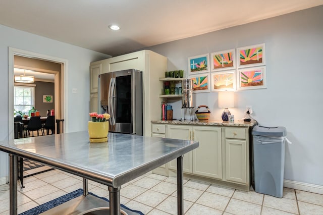 kitchen featuring light stone counters, stainless steel fridge, and light tile patterned flooring