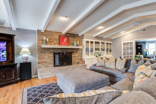 living room with vaulted ceiling with beams, hardwood / wood-style floors, and a fireplace