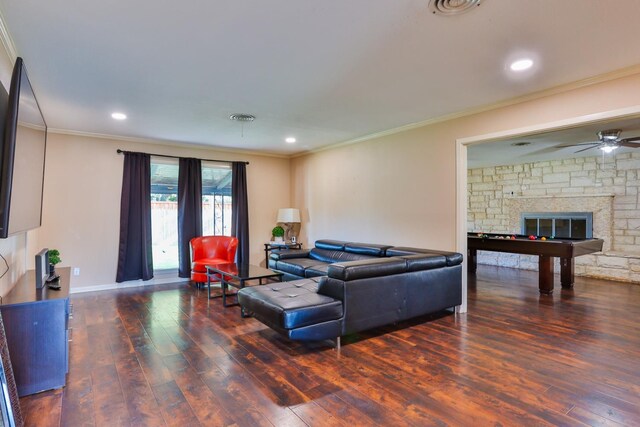 living room with billiards, ceiling fan, dark hardwood / wood-style floors, ornamental molding, and a stone fireplace