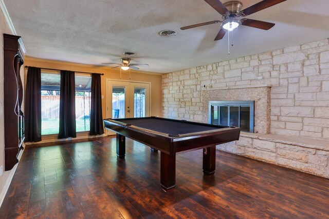 playroom featuring dark wood-type flooring, ceiling fan, a fireplace, a textured ceiling, and french doors