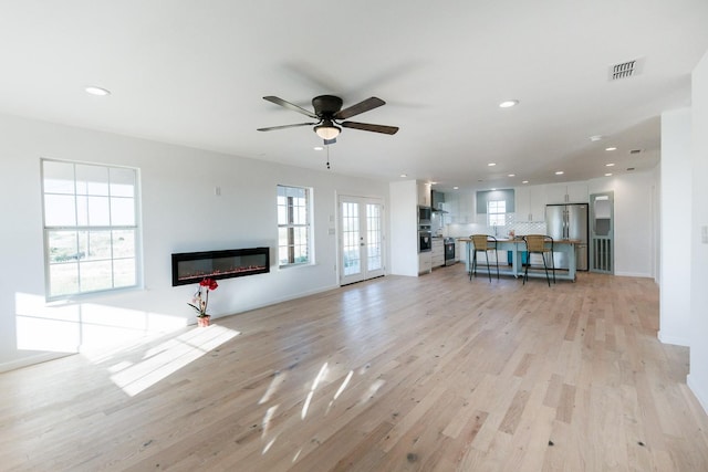 unfurnished living room featuring ceiling fan, light wood-type flooring, and french doors