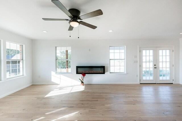 unfurnished living room with french doors, ceiling fan, and light wood-type flooring