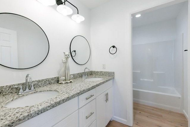 bathroom featuring wood-type flooring, bathtub / shower combination, and vanity