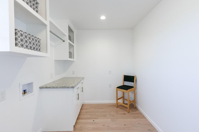 laundry room featuring washer hookup, cabinets, and light wood-type flooring