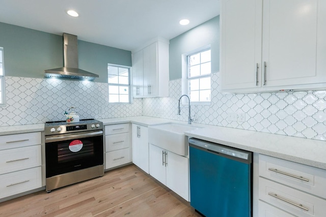 kitchen with stainless steel electric stove, dishwasher, sink, white cabinets, and wall chimney exhaust hood