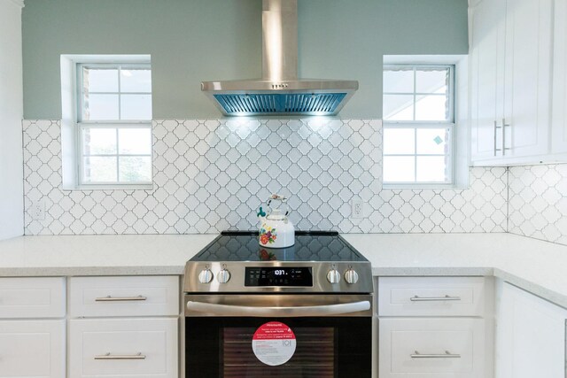 kitchen featuring decorative backsplash, exhaust hood, white cabinets, and stainless steel range with electric stovetop