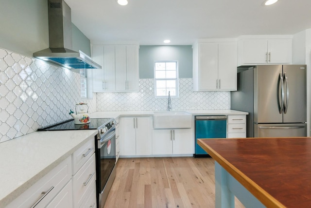 kitchen with appliances with stainless steel finishes, tasteful backsplash, sink, white cabinets, and wall chimney exhaust hood