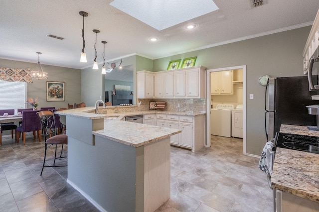 kitchen featuring pendant lighting, sink, independent washer and dryer, a kitchen bar, and kitchen peninsula