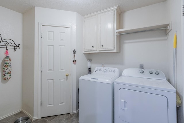 clothes washing area featuring a textured ceiling, cabinets, and washing machine and clothes dryer