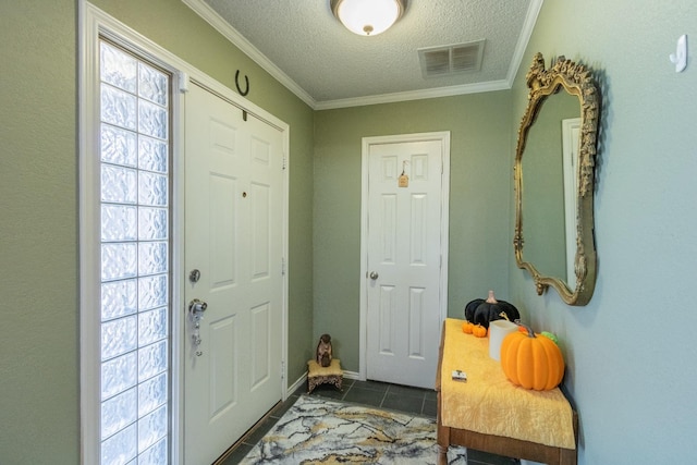 entrance foyer with dark tile patterned floors, crown molding, and a textured ceiling