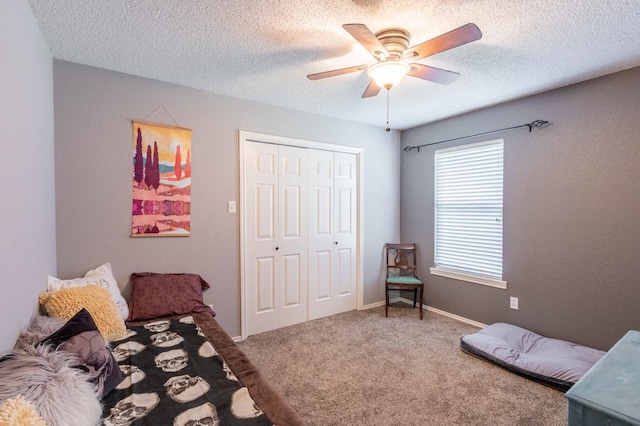 carpeted bedroom with ceiling fan, a textured ceiling, and a closet