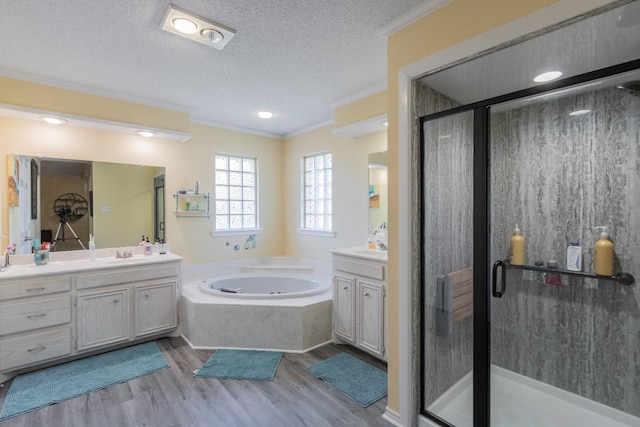 bathroom featuring hardwood / wood-style floors, vanity, ornamental molding, a textured ceiling, and separate shower and tub