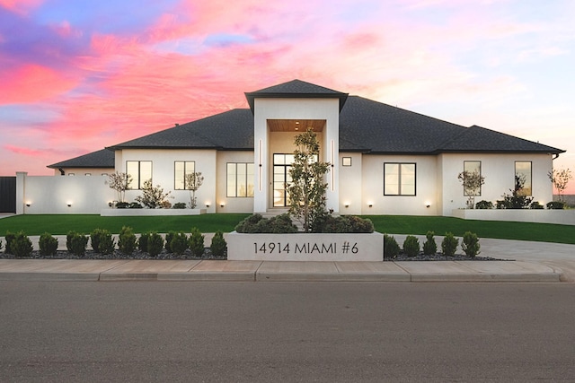 view of front of home with stucco siding, driveway, and a front lawn